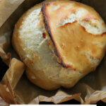 Pinterest pin for artisan bread with an image of a loaf of bread in a cast iron pan.