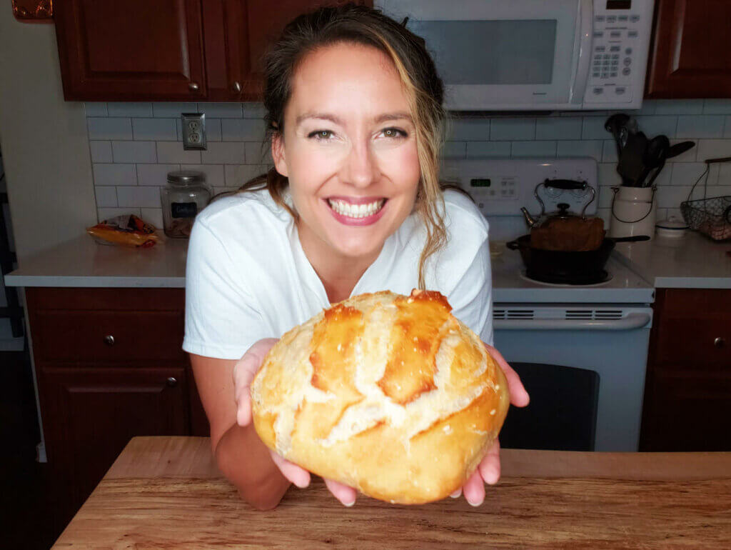 Woman holding up a loaf of artisan bread.