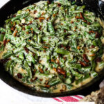 Pinterest pin with an image of a cast iron pan filled with creamy green bean casserole.