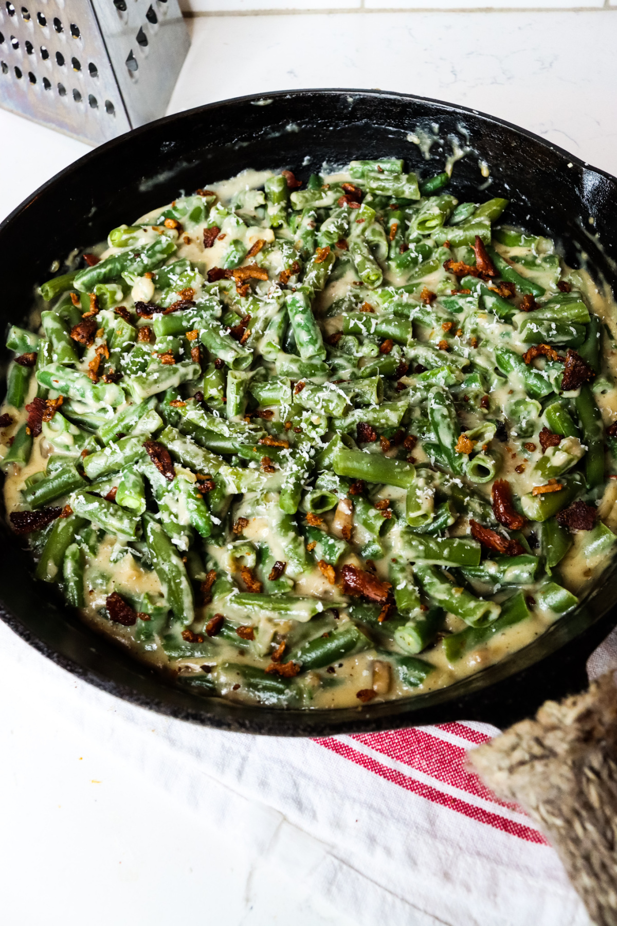 Cast-iron pan with creamy green bean casserole topped with bacon crumbles.