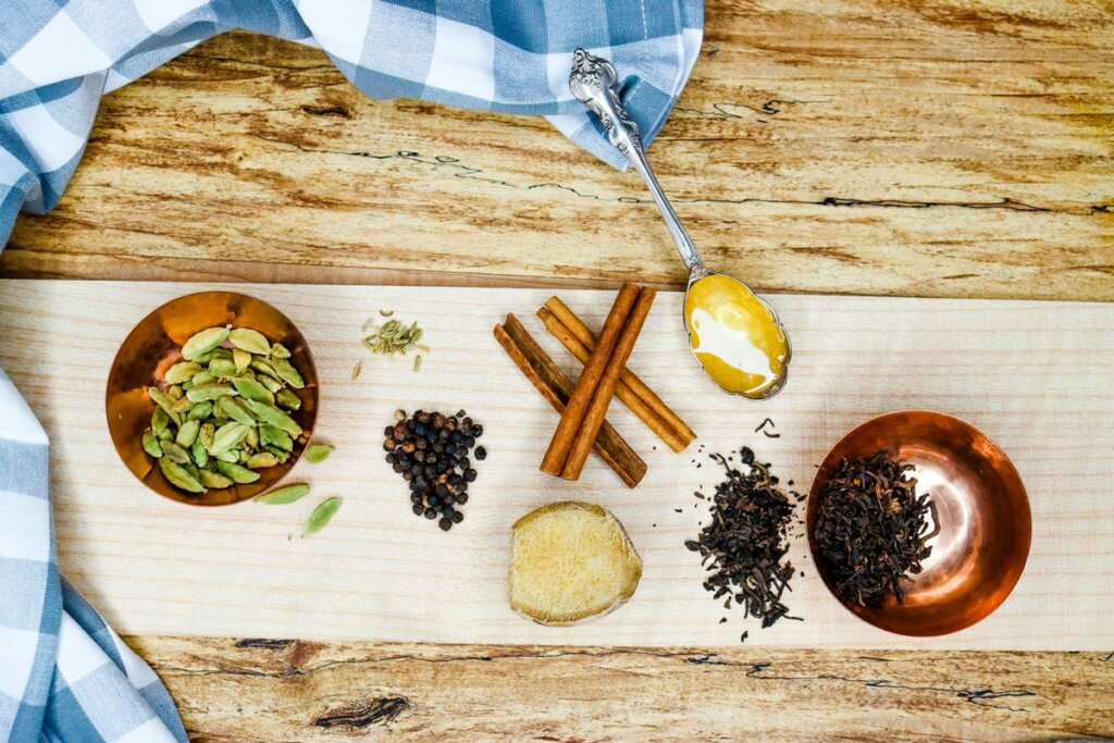 Ingredients for chai tea concentrate all measured and laid out on a wooden table.