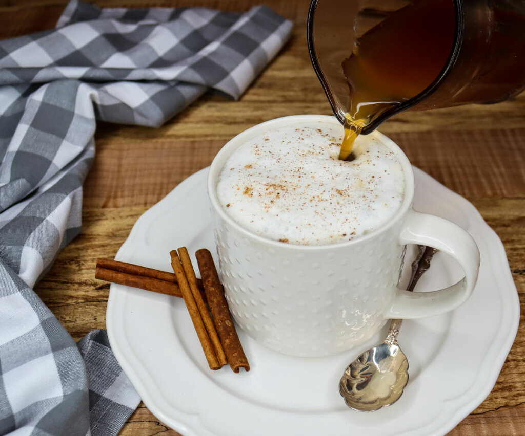 Photo of chai tea concentrate being poured into a cup filled with a chai tea latte.