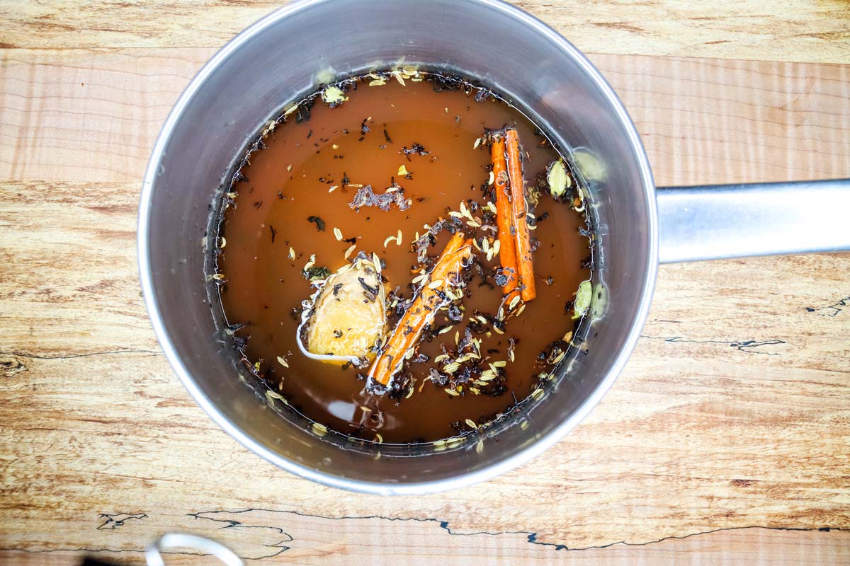 A pot filled with spices steeping in water for chai tea concentrate.