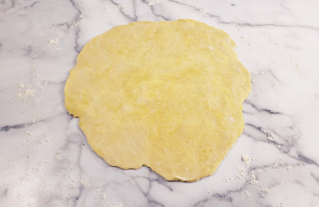 Pie dough rolled out into a circle on a countertop.