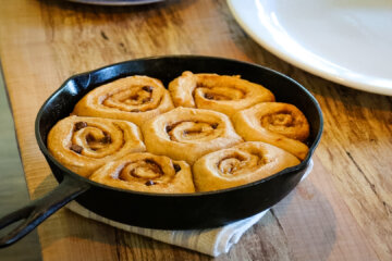 Chocolate caramel cinnamon rolls baked in a cast iron pan sitting on a table.