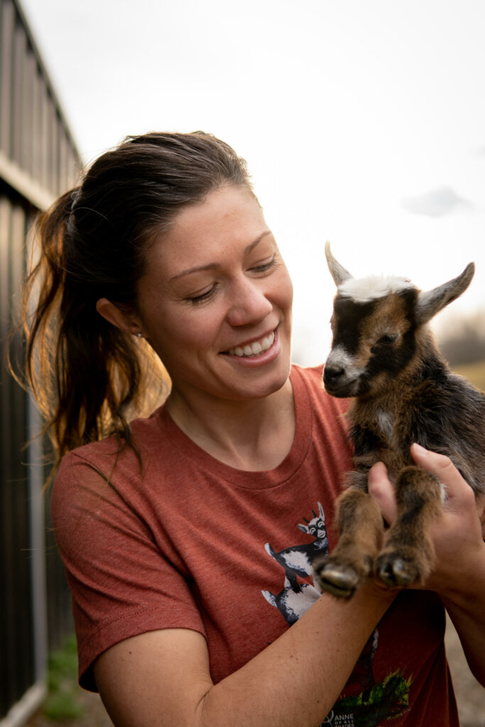 A woman holding a baby goat.