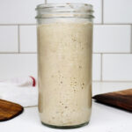 Sourdough starter in a jar on a counter.