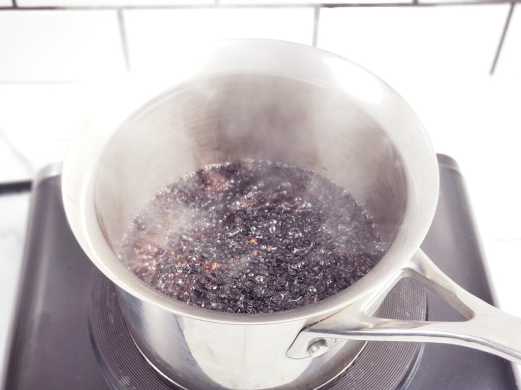 A pot simmering with elderberries and water.