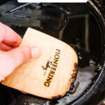 Pinterest pin for how to clean cast iron with an image of a dirty cast iron pan being cleaned.