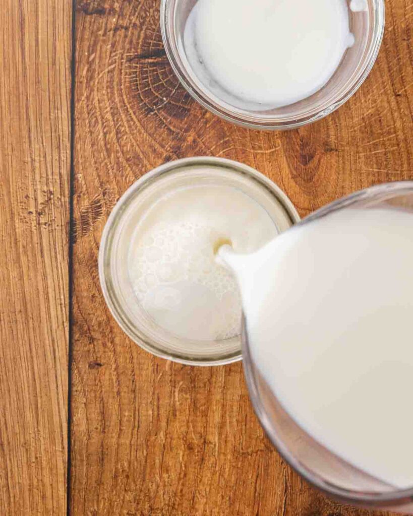Pouring milk into a glass jar to make homemade buttermilk.