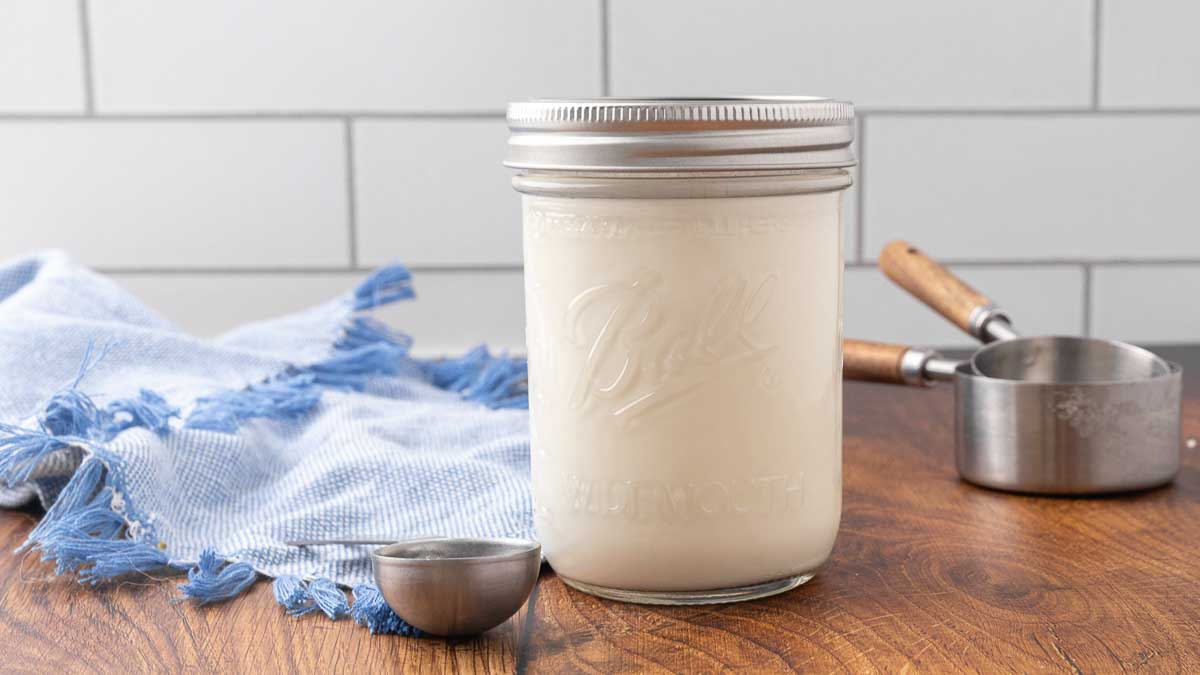 A jar of homemade buttermilk sitting on a counter.
