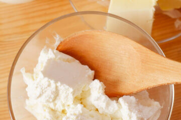 A bowl of cultured cheese with a wooden spoon.
