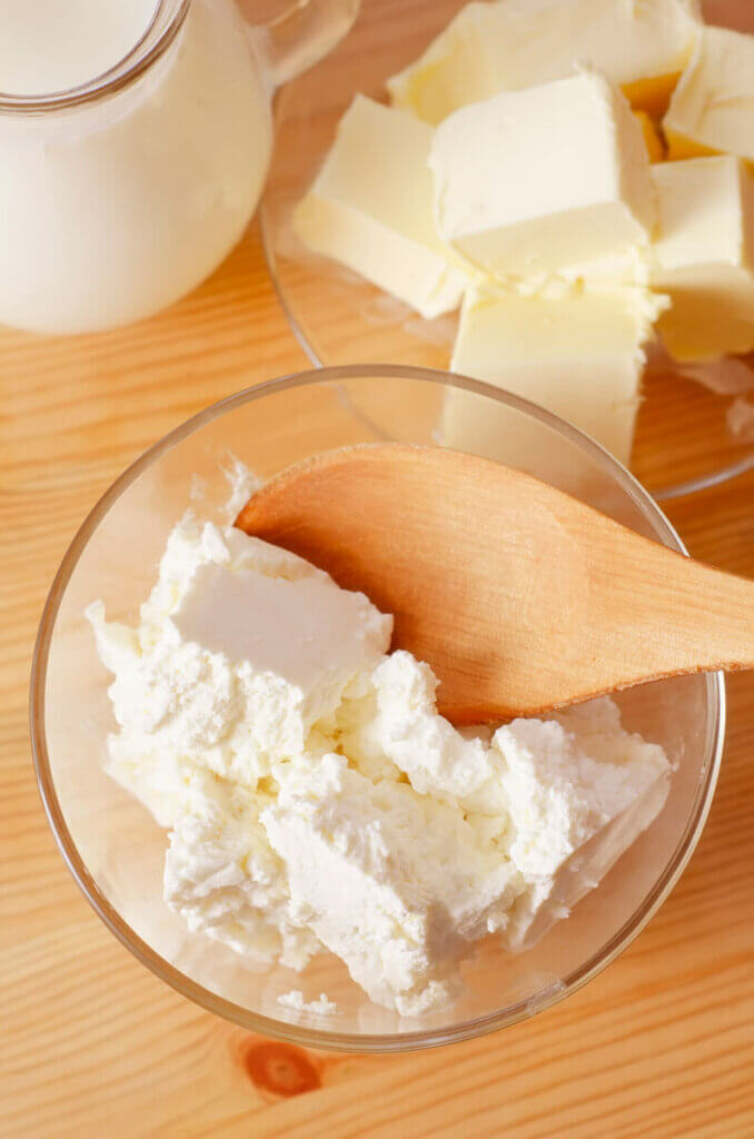 A bowl of cultured cheese with a wooden spoon.