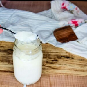 A spoon scooping buttermilk out of a mason jar.