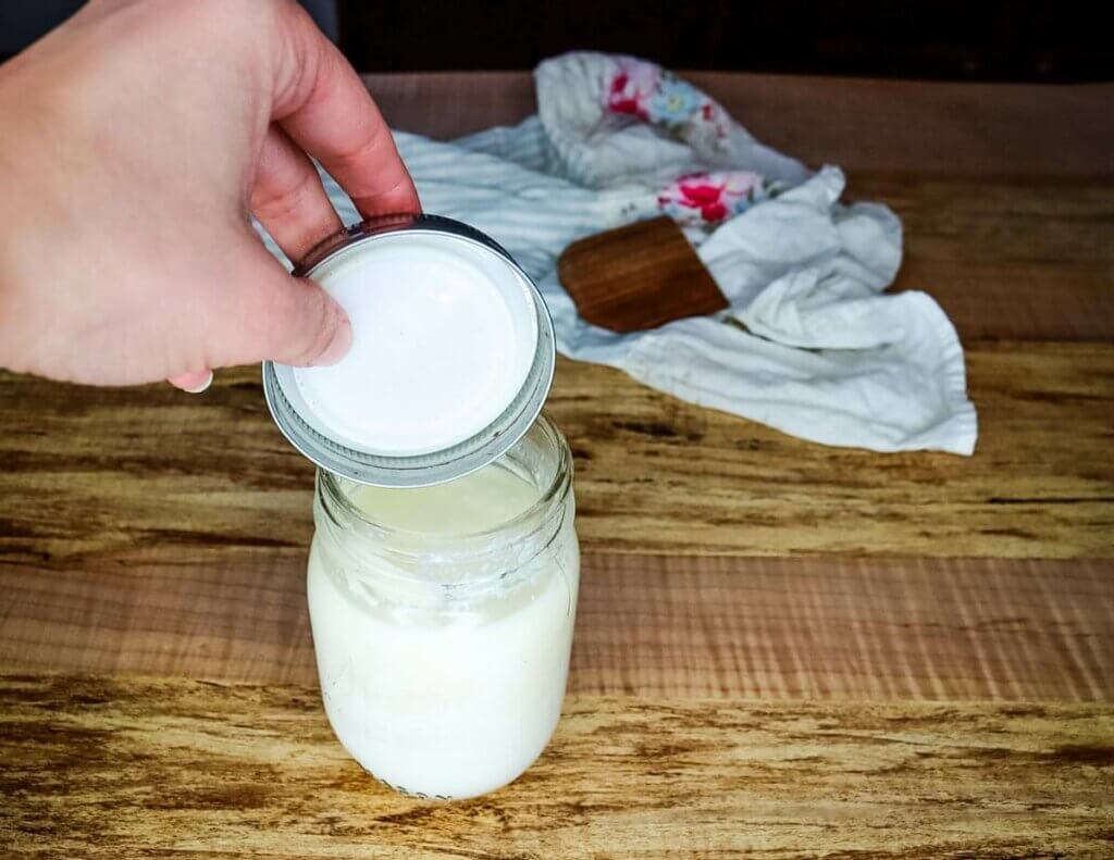 A lid being put onto a jar of cultured buttermilk.