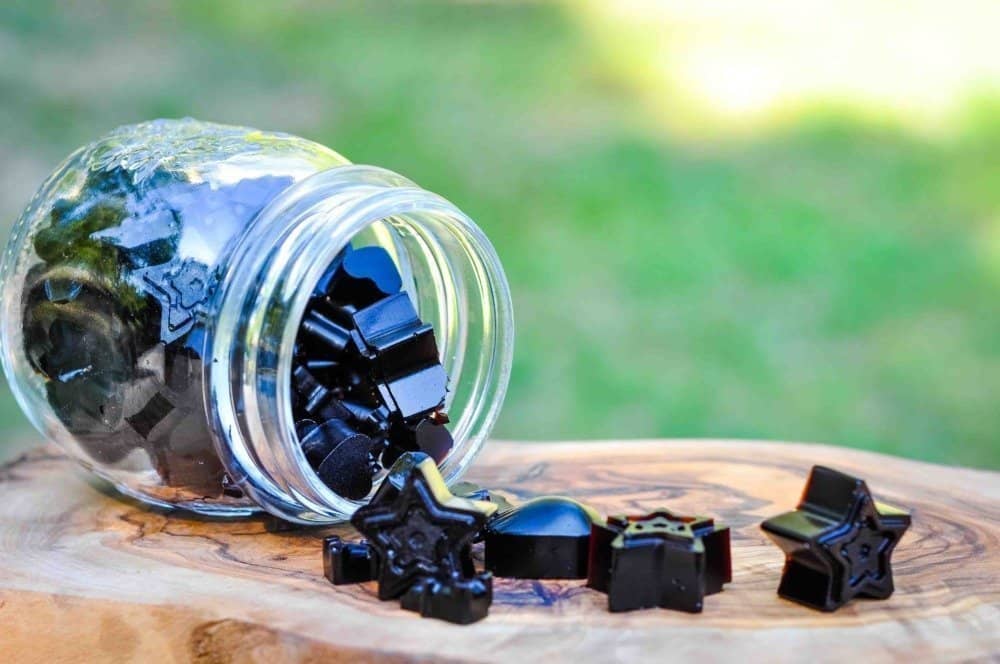 Elderberry gummies in a jar spilled over onto a table.