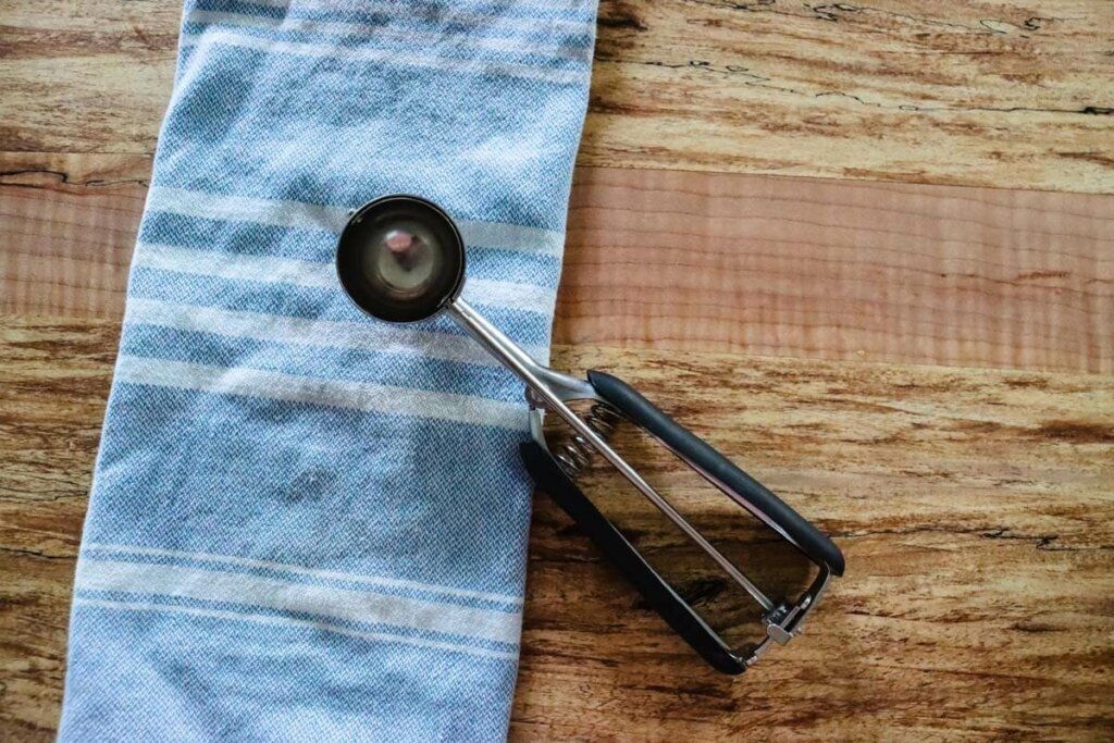 An ice cream scooper, or a cookie scoop, sitting on the kitchen counter.