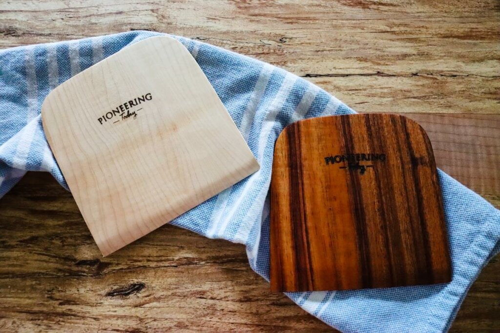 Wooden bench knives laying on a tea towel.