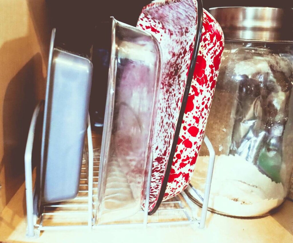 Pots and pans organized in a kitchen cupboard with a rack organizer.