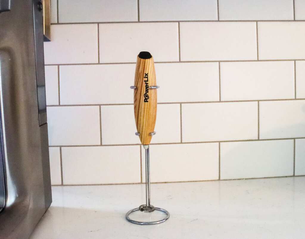 A small whisk wand/electric frother sitting on a kitchen counter.