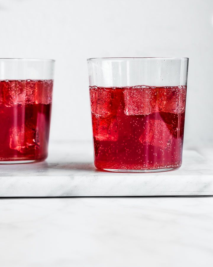 Two glasses of elderberry kombucha with ice.