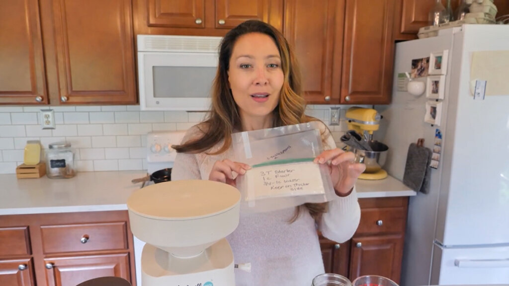 Image of a woman holding up a ziplock of dehydrated sourdough starter.