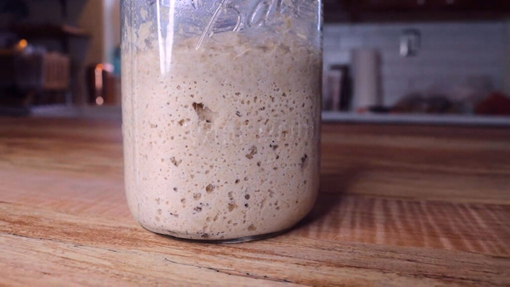 Image of bubbly sourdough starter in a glass mason jar.