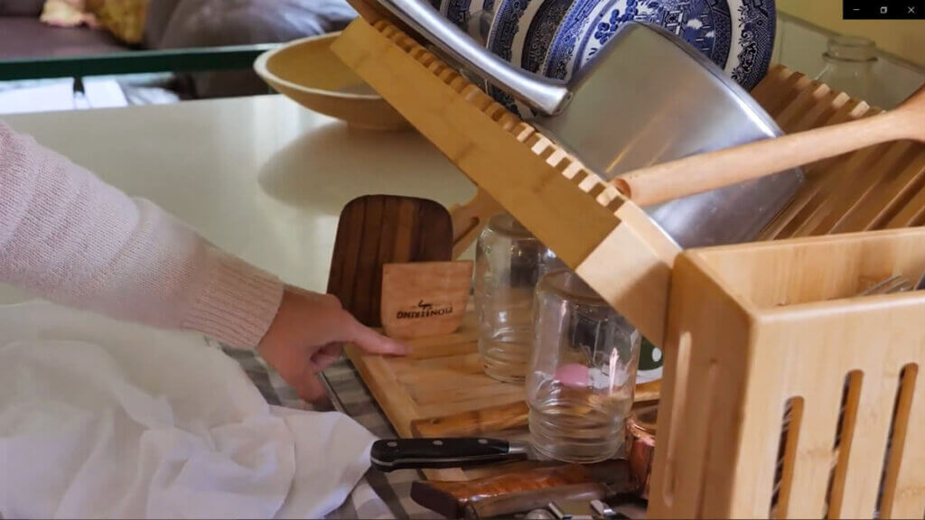 A wooden drying rack with various wooden utensils drying on it.