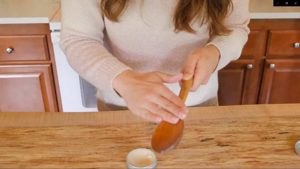 Image of a woman conditioning a wooden spoon with wood butter.