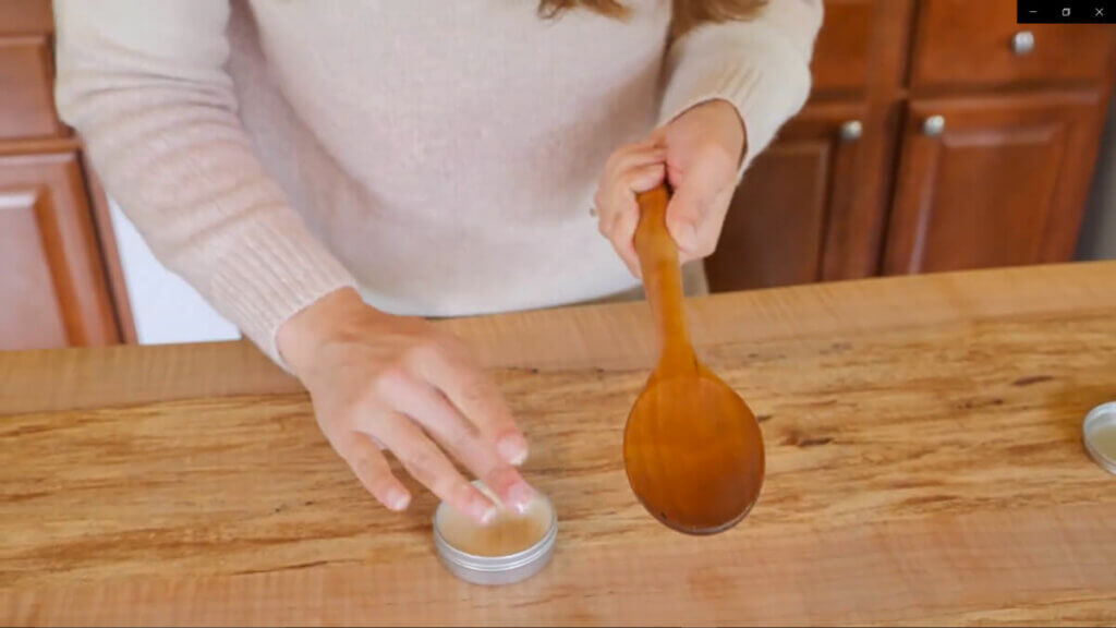 Image of a woman conditioning a wooden spoon with wood butter.