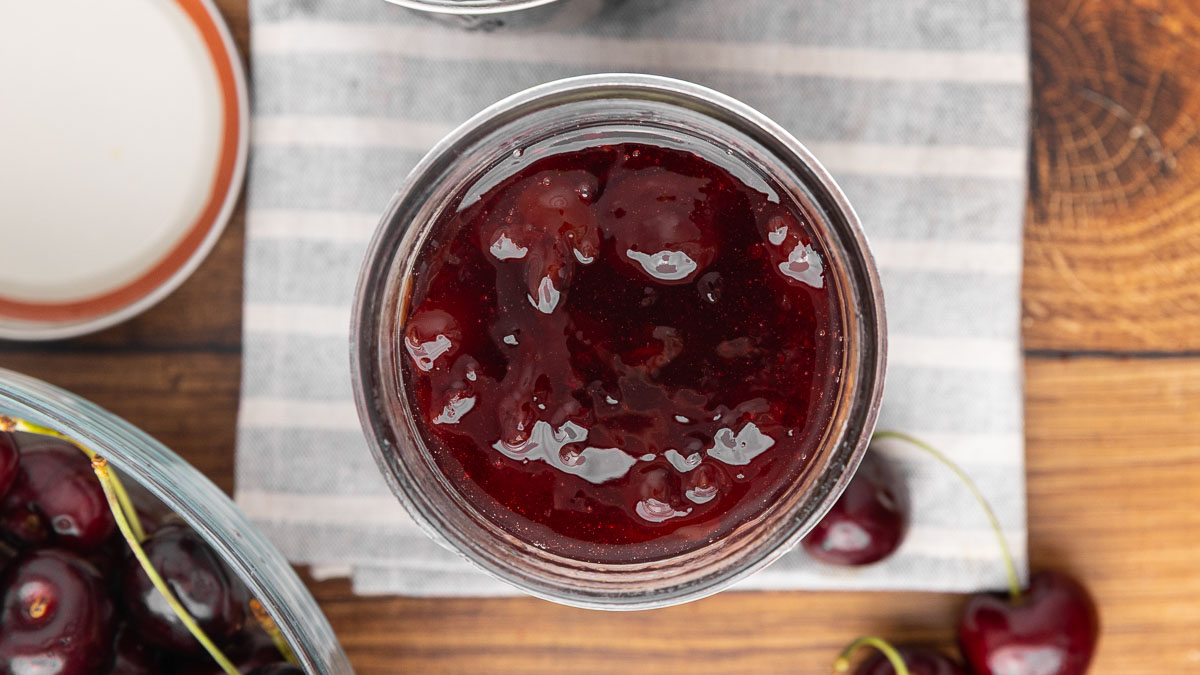 A bird's eye view of a jar full of cherry jam.