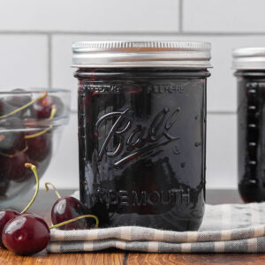 Two sealed jars of cherry jam.