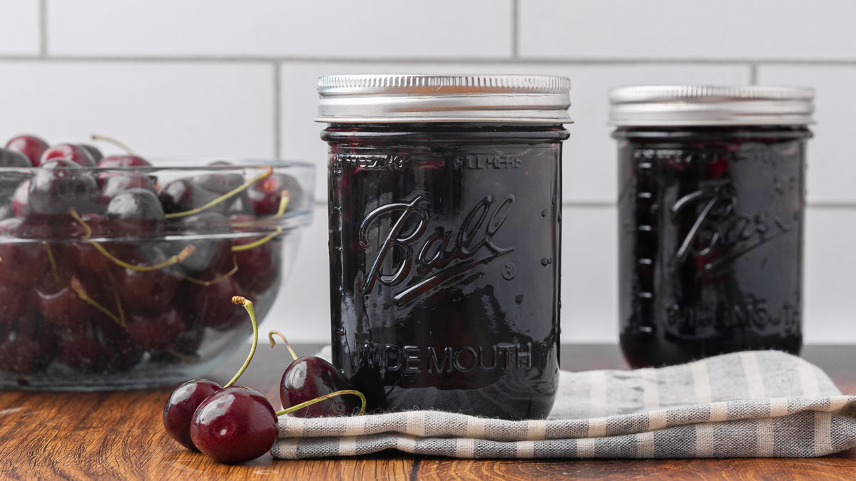 Two sealed jars of cherry jam.
