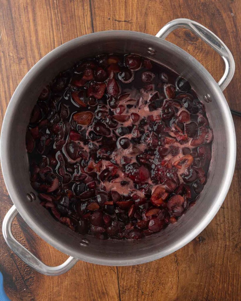 Cherries cooking in a stockpot.