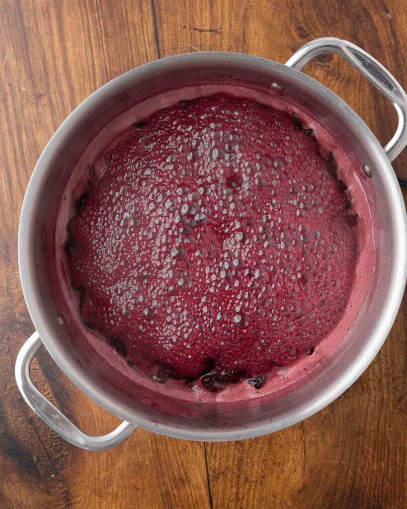 A stockpot full of cherry jam that has reached the gel point.