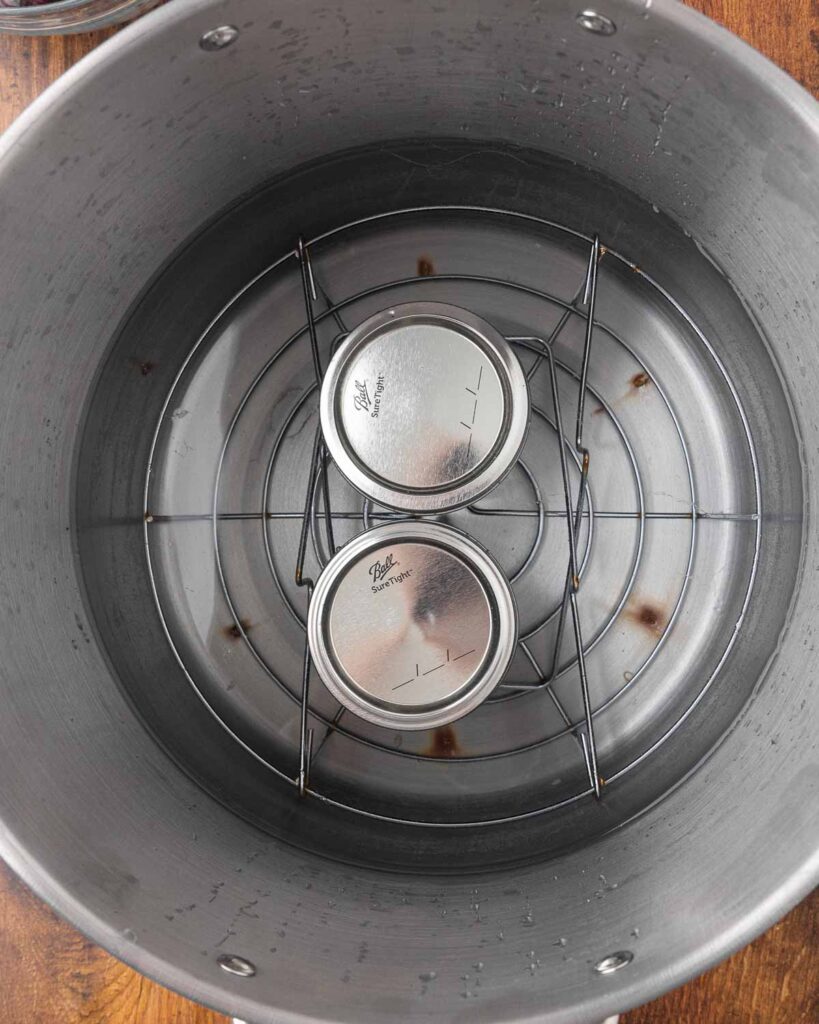 A bird's eye view of jars of cherry jam in a water bath canner.