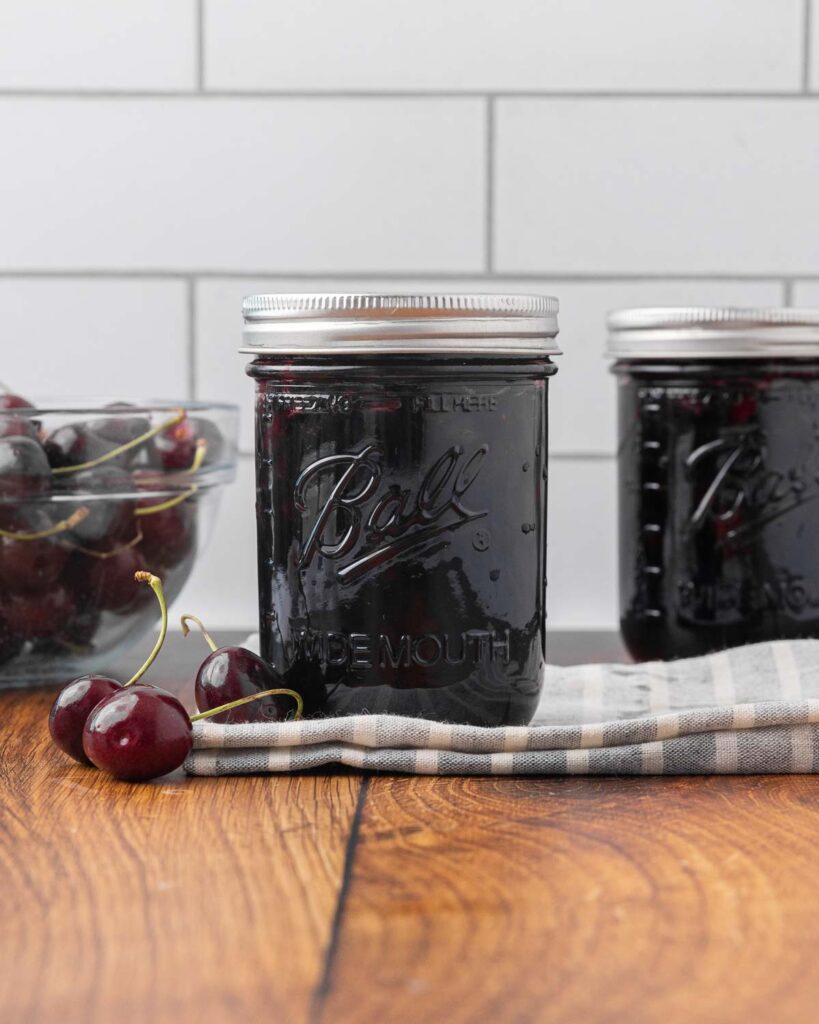 Two sealed jars of cherry jam.