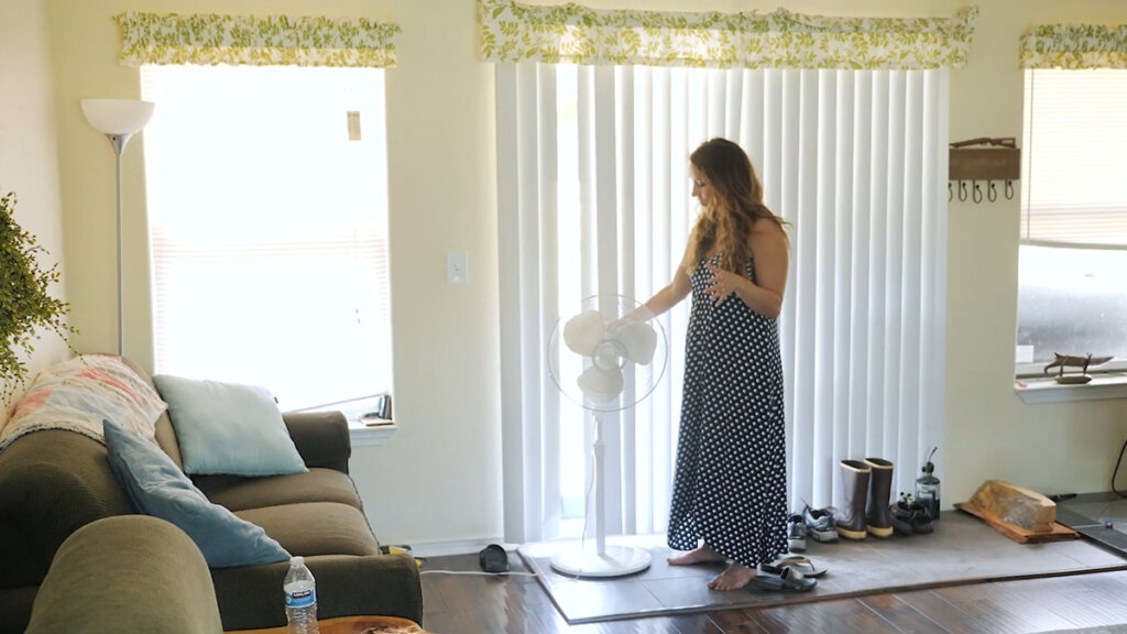 A woman standing in front of a large sliding door with a fan in front of the door.