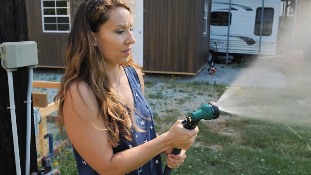 A woman spraying a hose with a nozzle attachment.