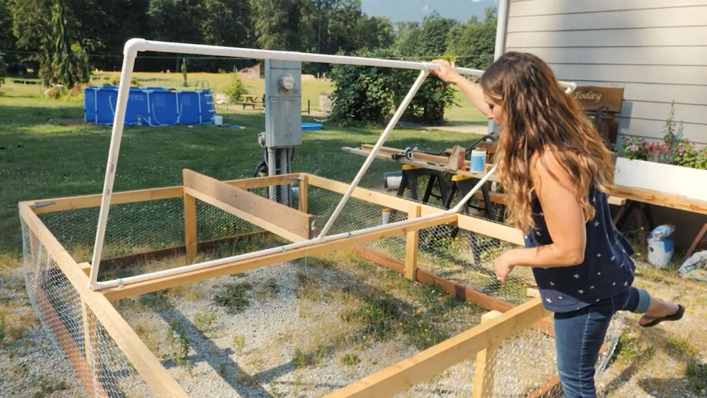 Woman standing beside a DIY mobile chicken tractor.