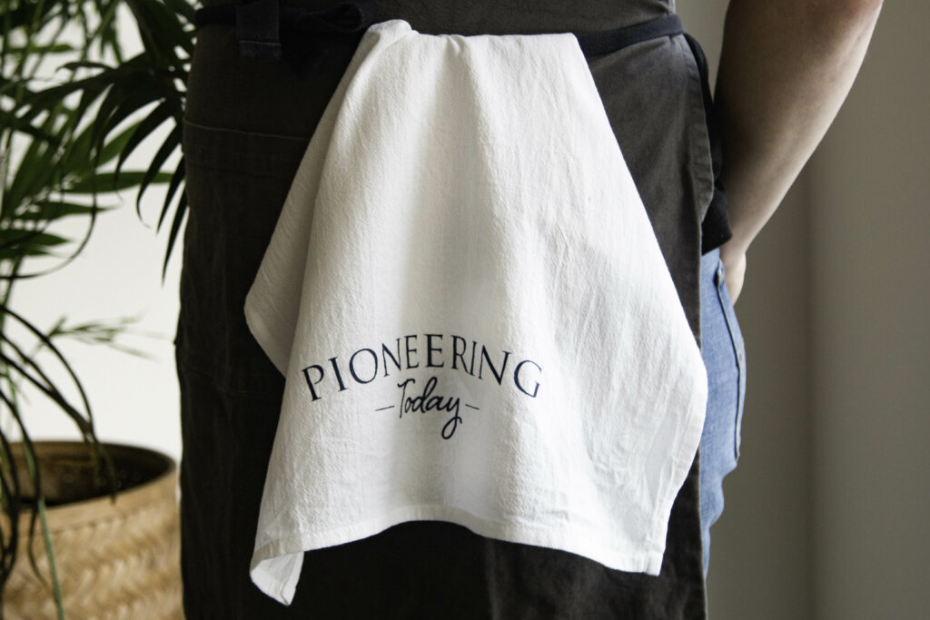 Pioneering Today Cotton Tea Towel tucked into apron around woman's waist
