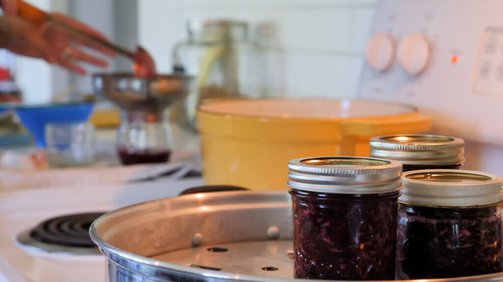 Three jars of cherry jam sitting in a steam canner.