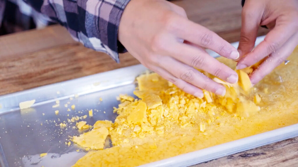 A woman's hands crumbling freeze dried eggs into powder.