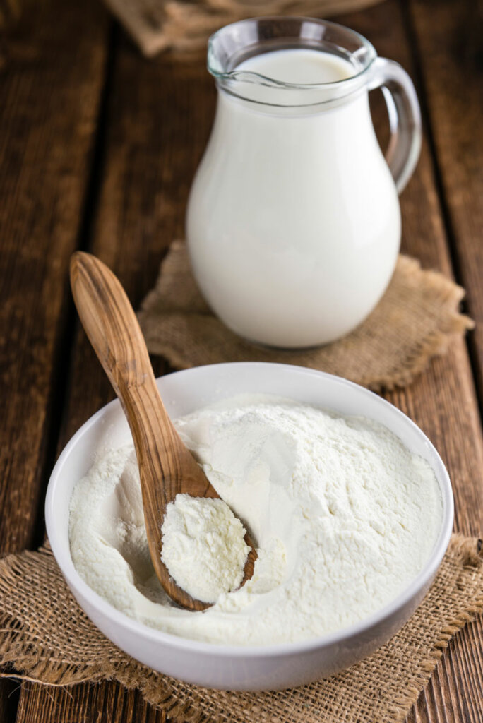 Freeze dried milk powder in a bowl next to a pitcher of milk.