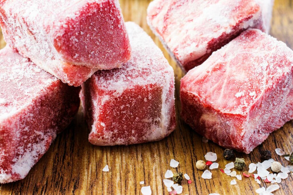 A pile of steaks on a wooden cutting board.