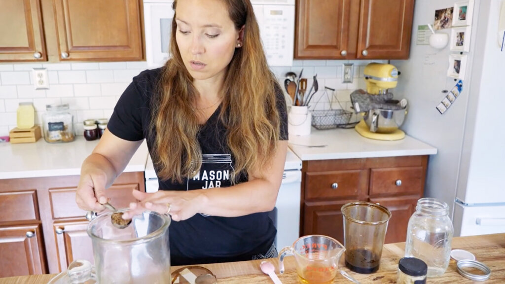 A woman measuring out brown sugar to add to ginger water.