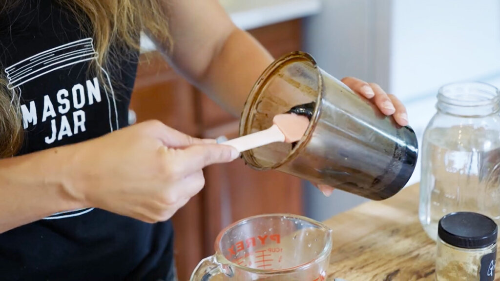 A woman measuring out molasses to add to ginger water.