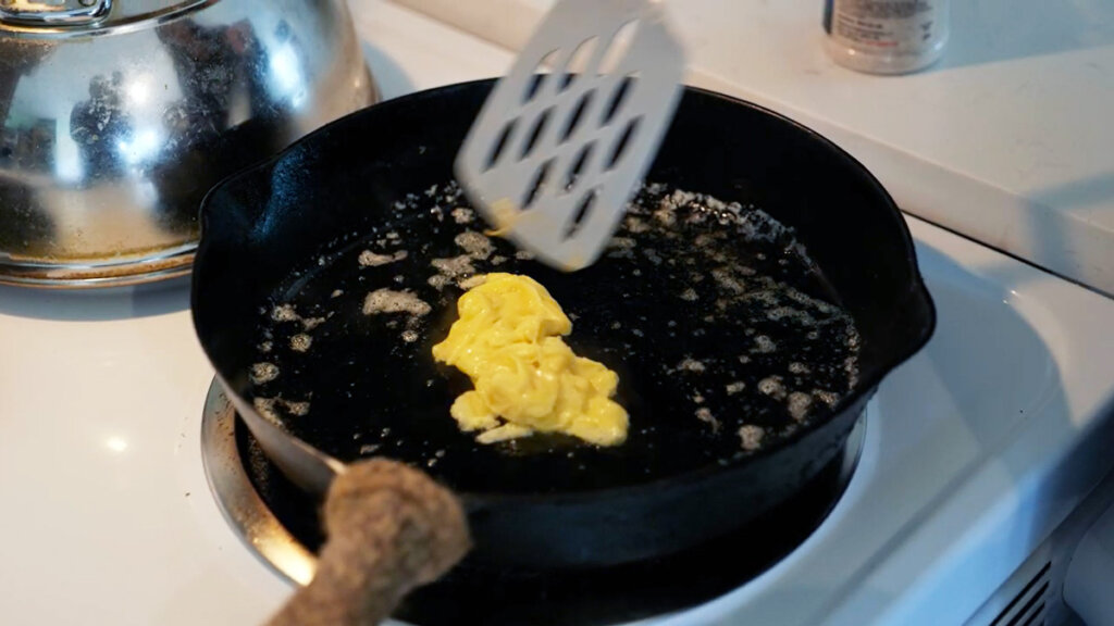 Scrambled eggs cooking in a cast iron pan.