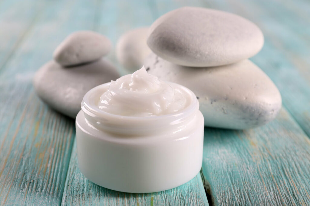 A jar of lotion with stones in the background.