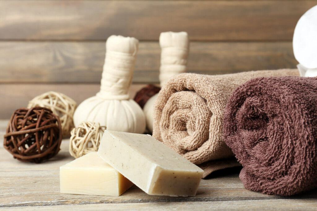 Two bars of soap on a counter with rolled up towels in the background.